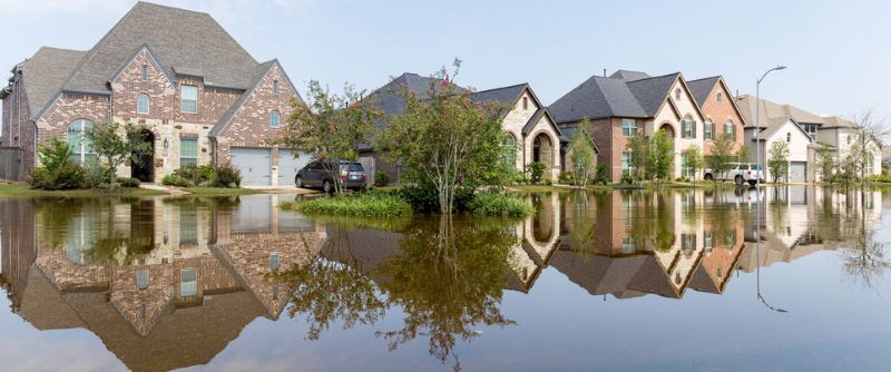 A suburban neighborhood with flooded streets and water covering the yards.