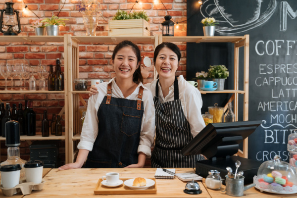 Two smiling people working in a coffee shop.