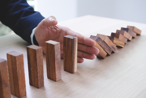 Hand pushing dominos down